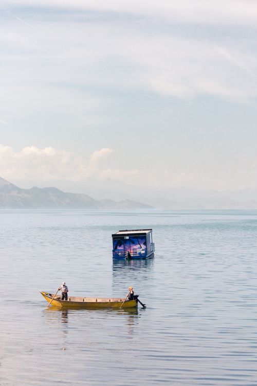 Free Peaceful view of two boats on Lake Shkodër, Albania, surrounded by serene waters and distant hills. Stock Photo