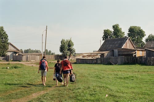 People Walking on the Green Grass Field Near Wooden Houses