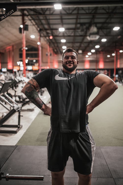 A Brawny Man in Black Activewear Flexing His Muscles