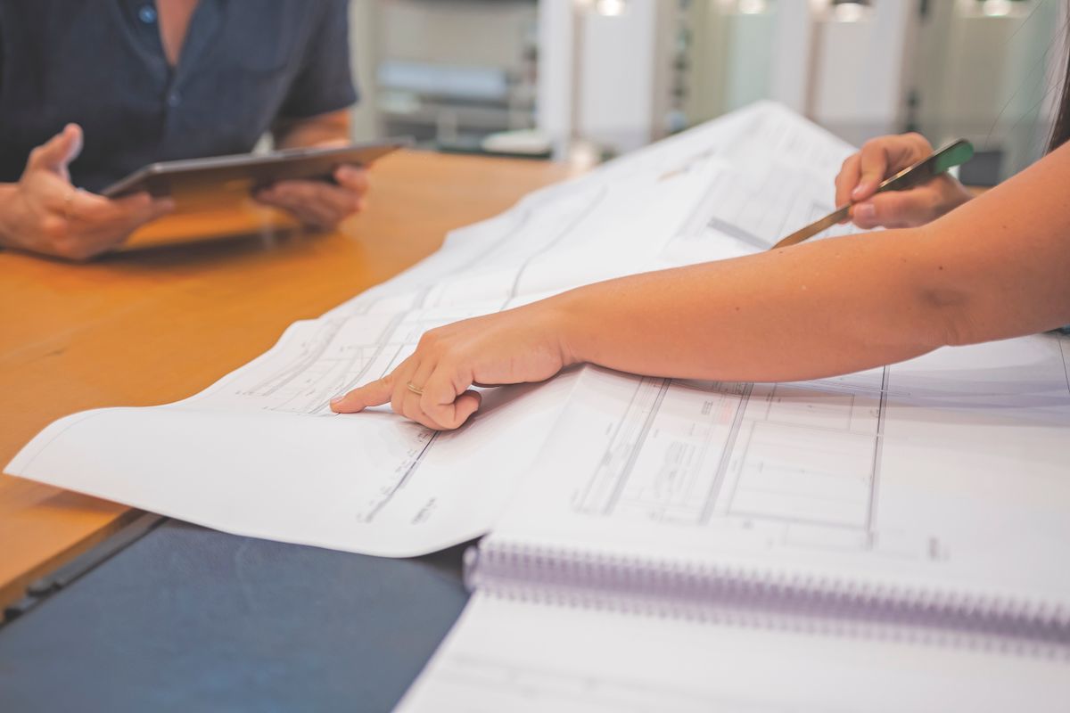 Two colleagues collaborating on blueprints in a modern office