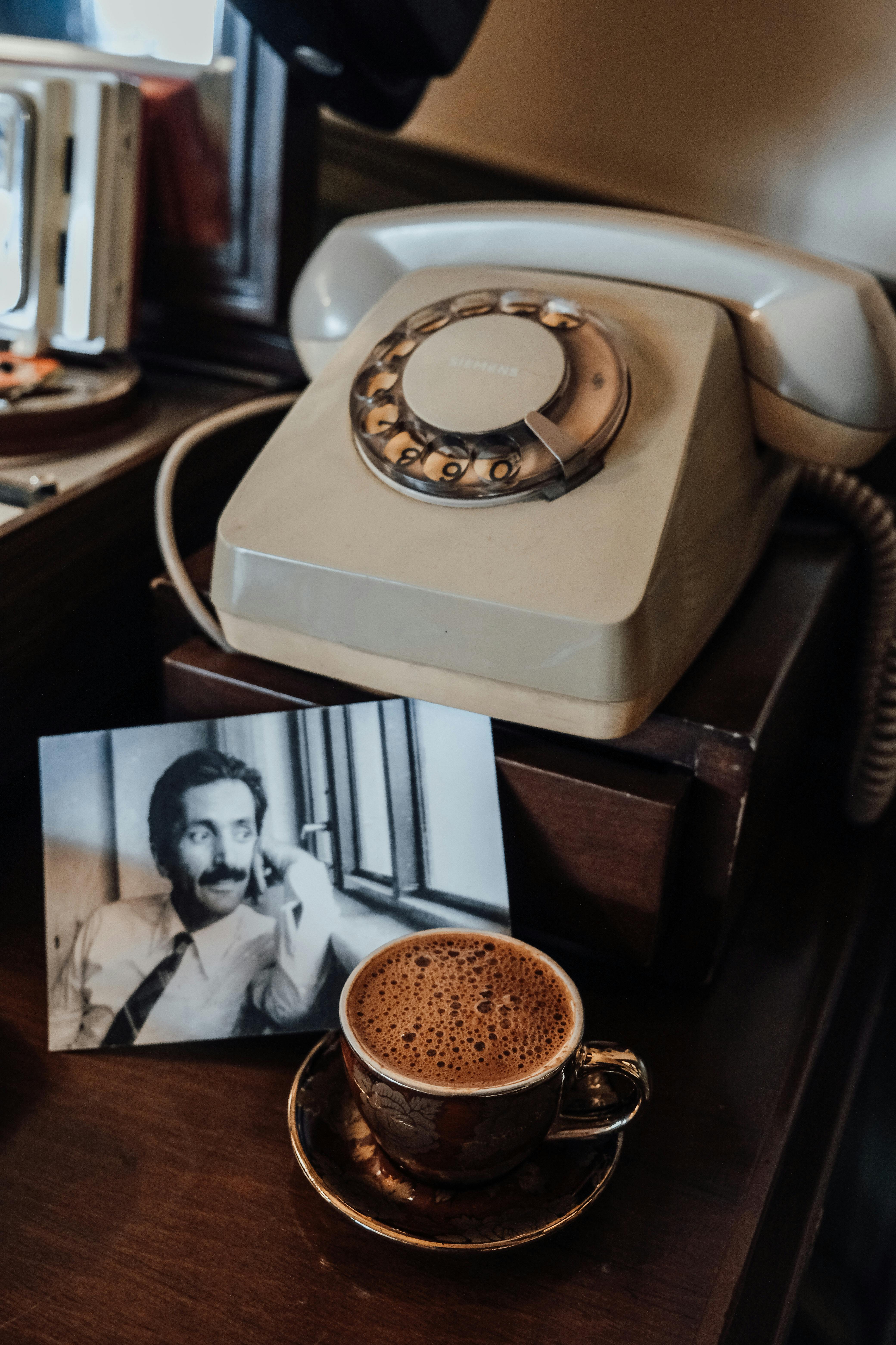 A nostalgic still life featuring a rotary phone, Turkish coffee, and a sepia-toned photo.