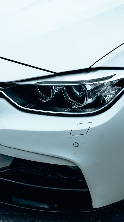 Free Detailed close-up of a sleek white car's headlight showcasing modern design and clear lines. Stock Photo