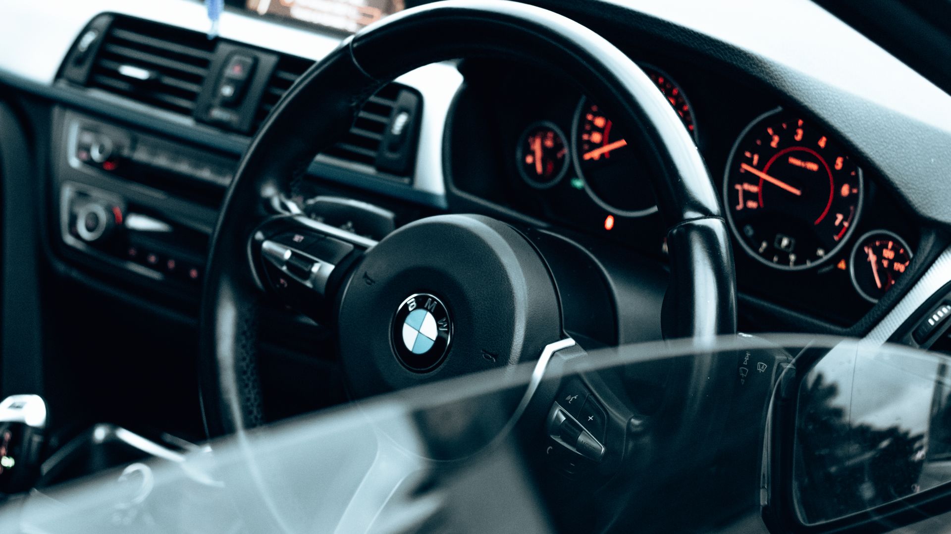 Detailed view of BMW car interior showing the steering wheel and illuminated dashboard gauges.