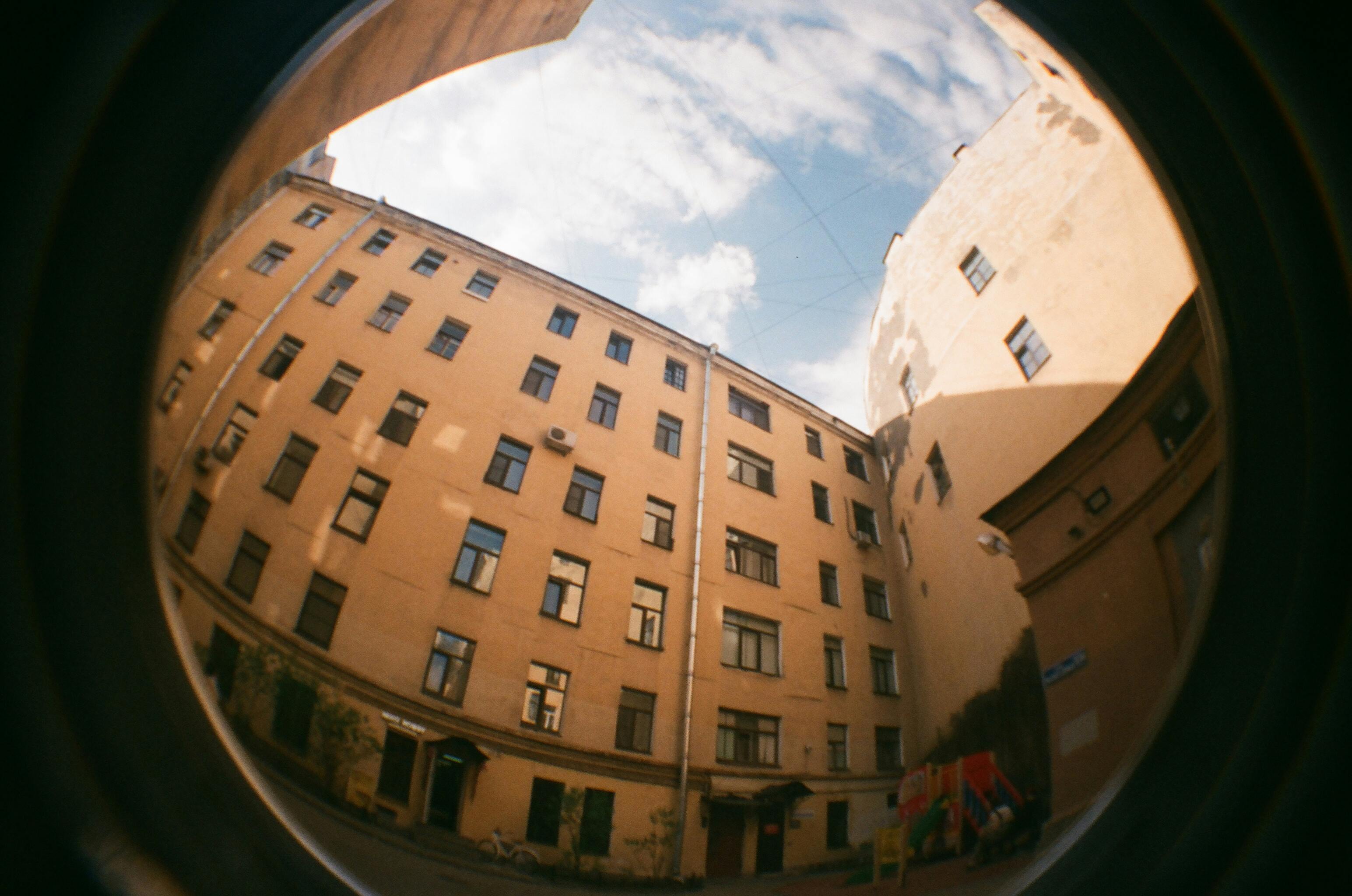 Fisheye photo capturing a low angle view of an urban apartment complex with glass windows.
