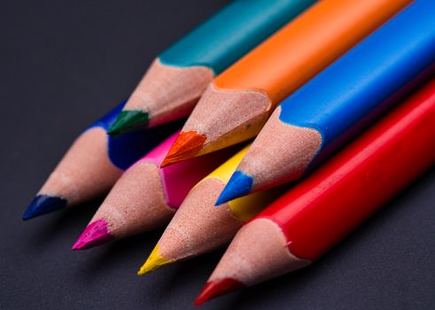 Close-up of colorful sharpened pencils against a dark backdrop, showcasing vivid hues.