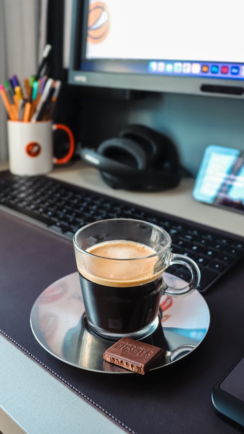 A Glass Mug with Coffee and a Chocolate Bar on a Saucer