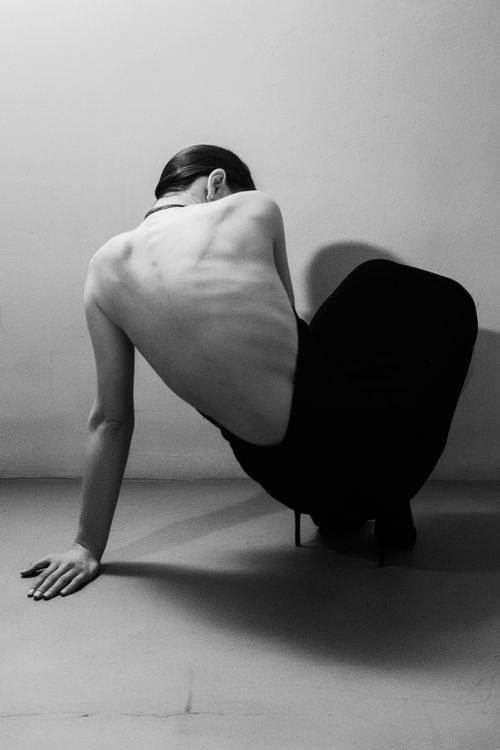 Free Artistic black and white photo of a crouching woman in a backless dress, highlighting fashion and form. Stock Photo