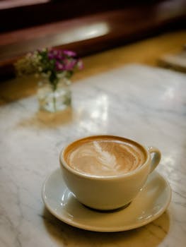 Delight in a freshly brewed cappuccino against a cozy cafe backdrop on marble.