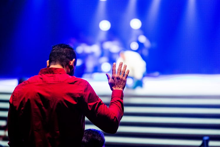 Back View Of A Man Wearing Red Shirt, And Blue Illuminated Stage