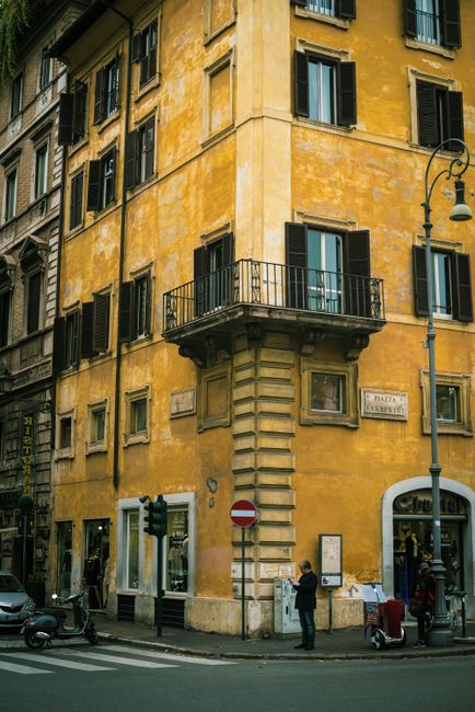 Explore a vibrant yellow building corner in Rome's bustling cityscape.