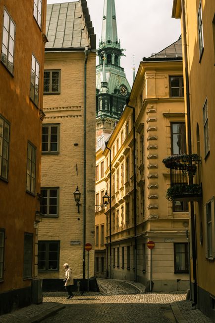 Quaint Stockholm street scene showcasing historic architecture and a person walking against a backdrop of classic buildings.
