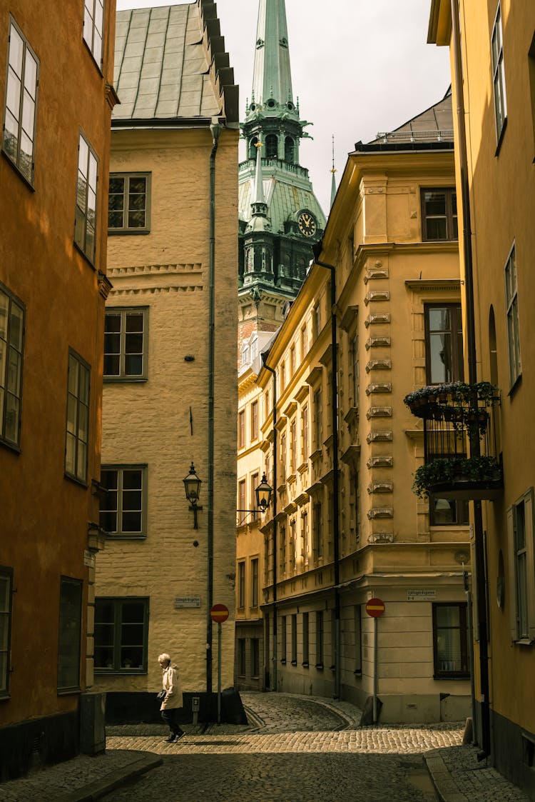 A Person Crossing Street Between Buildings