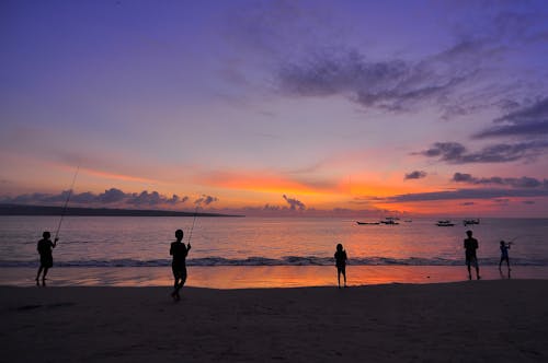 Siluet Lima Orang Berdiri Di Pantai Saat Matahari Terbenam