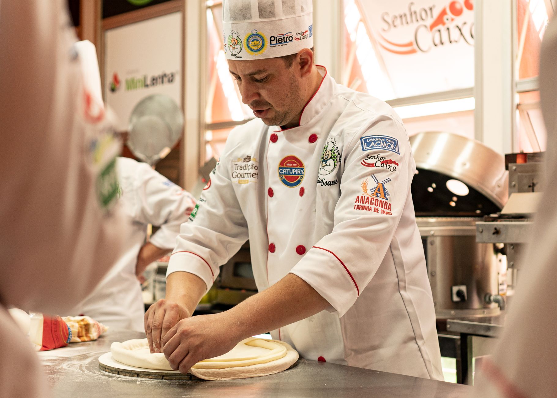 Chef kneading dough in a professional kitchen, showcasing culinary skills and uniform details.