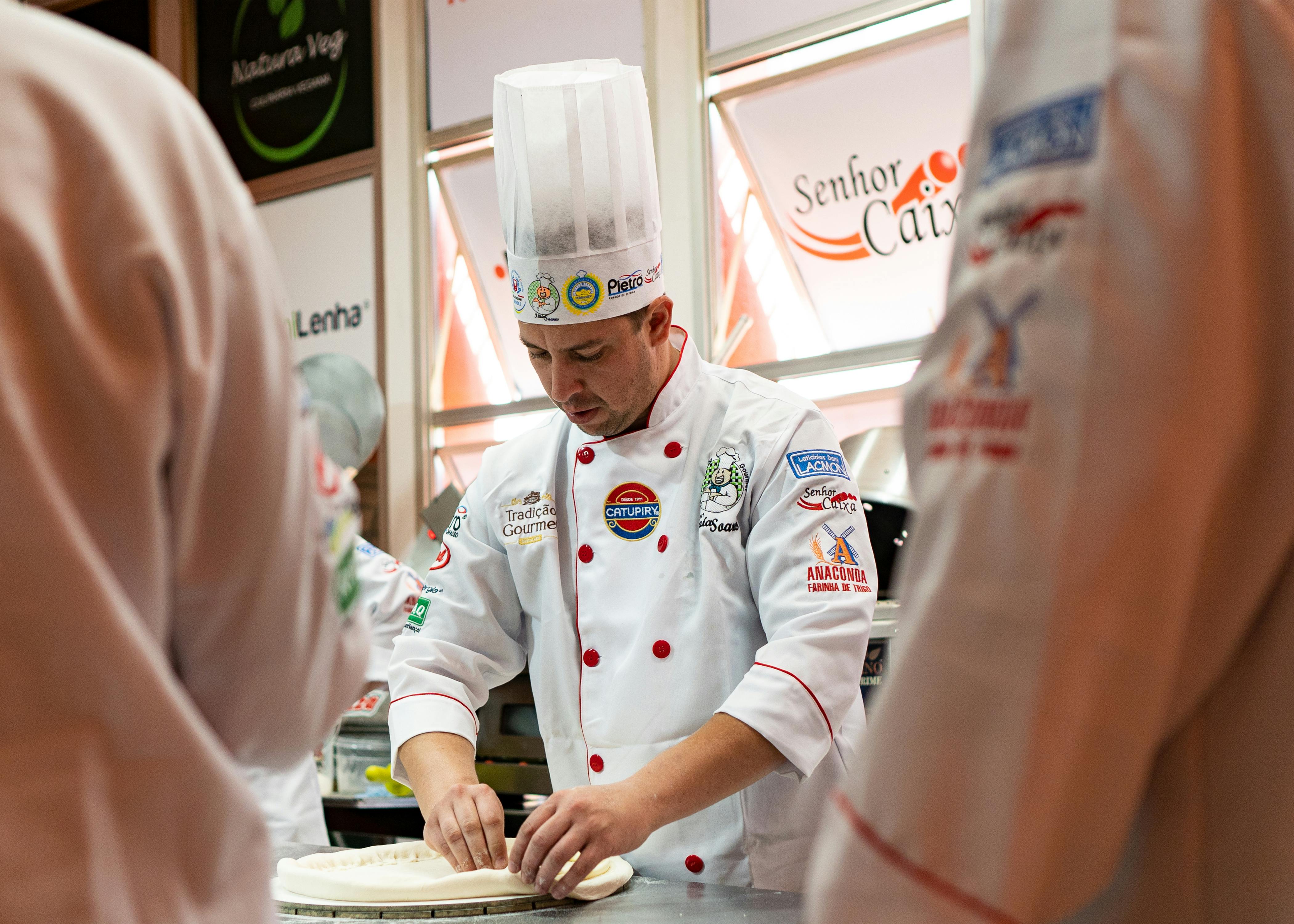 Chef in kitchen expertly preparing gourmet pizza dough, wearing a traditional chef hat and uniform.