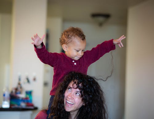 Photo of Woman Carrying Her Child on Her Shoulder