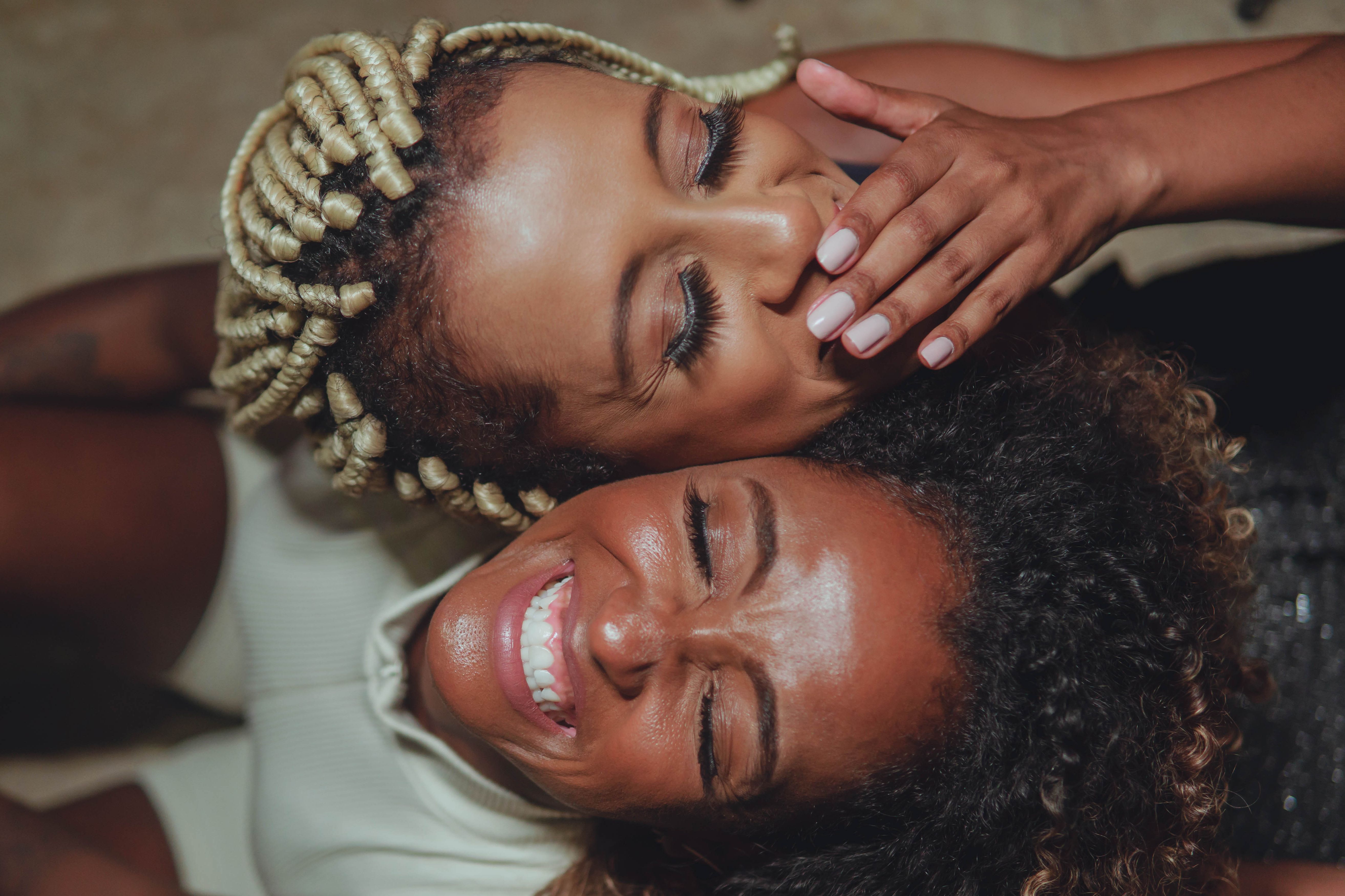 Close-up of two happy friends laughing together, capturing a moment of joy.