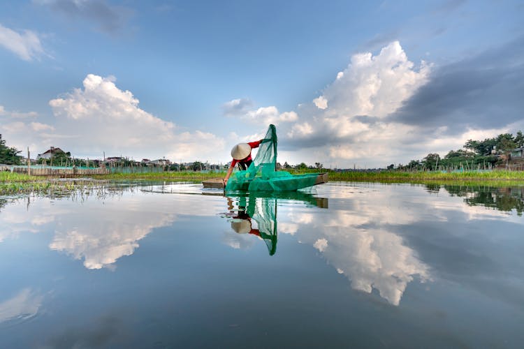 A Fisherman On A Boat Holding A Green Net