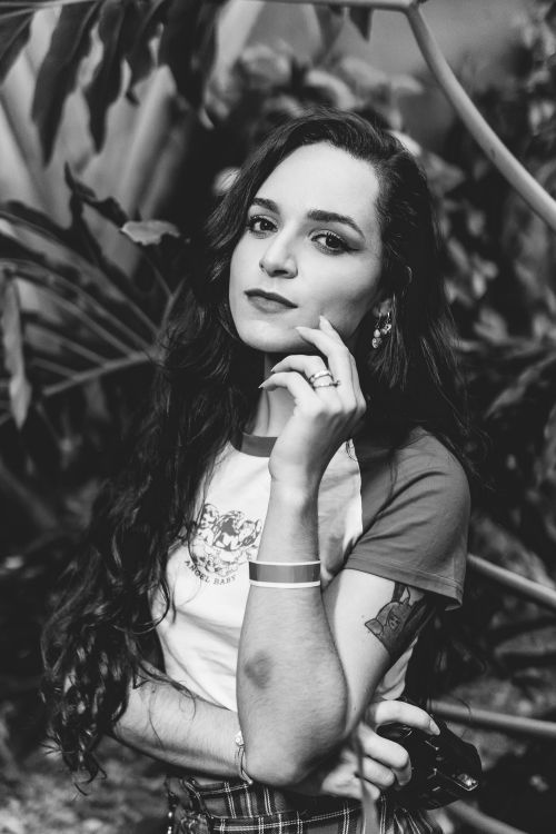 Free A captivating black and white portrait of a woman with wavy hair, posing in an outdoor setting. Stock Photo
