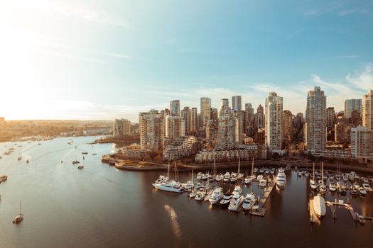 A panoramic view of Vancouver's skyline and marina at sunset, showcasing high-rise buildings and boats.