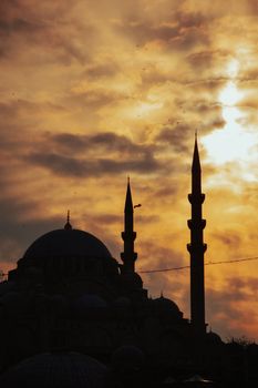 A mosque silhouette with minarets set against a dramatic sunset sky, conveying tranquility.