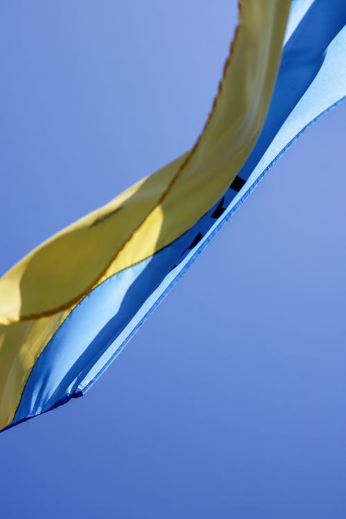 Free Ukrainian Flag Waving in Wind with Clear Sky in Background Stock Photo