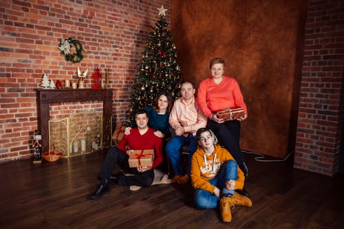 A Group of People Sitting Beside a Christmas Tree During Christmas Celebration