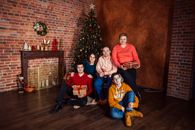 A Group of People Sitting Beside a Christmas Tree During Christmas Celebration