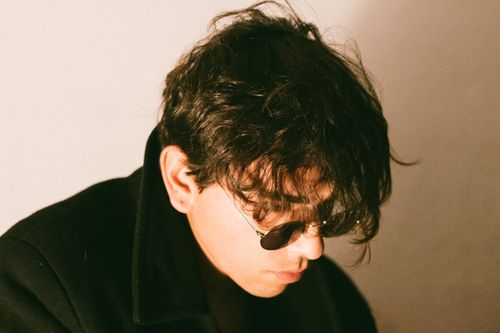 Free Close-up of a fashionable young man with sunglasses, casting a soft light ambiance. Stock Photo