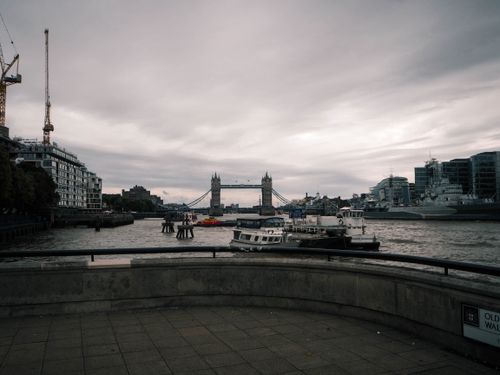 Free Overcast view of Tower Bridge on the Thames River with ships and city skyline in London. Stock Photo