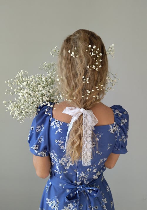Back View Shot of a Woman in Blue Dress Holding Baby's Breath Flower