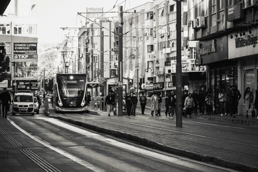 Monochrome image depicting a bustling city street with a tram and numerous pedestrians. Ideal for urban lifestyle topics.