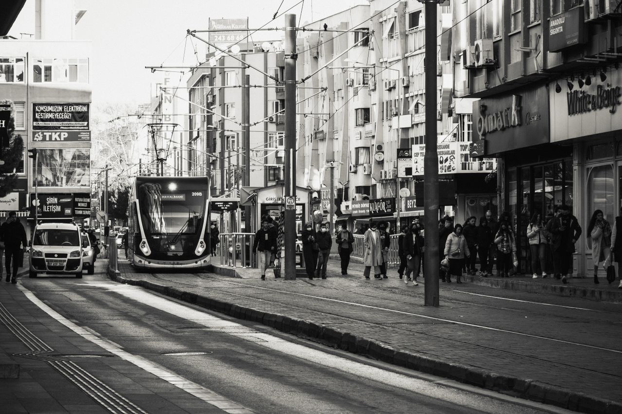 monochrome image depicting a bustling city street with a tram and nume