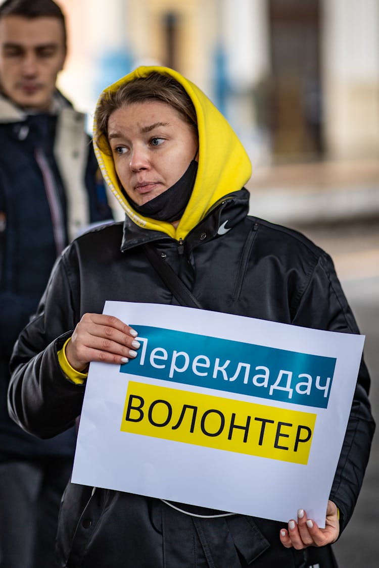 A Translator In A Yellow Hoodie Holding A Placard