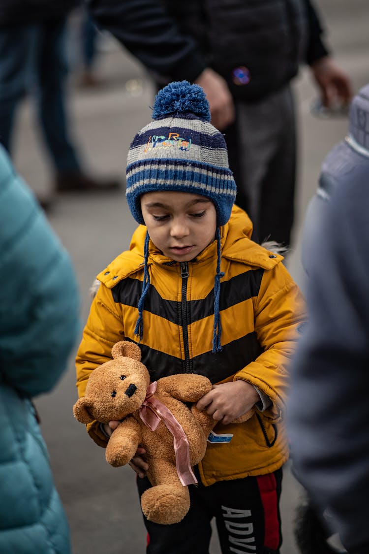 A Child Carrying A Teddy Bear