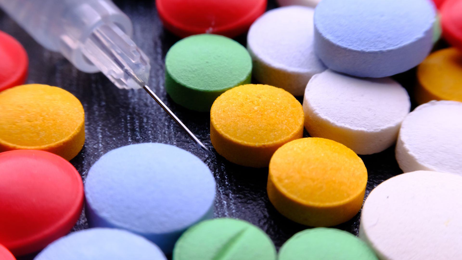 Modafinil Addiction Potential: Exploring the Risks and Benefits Vibrant close-up of assorted pills and a syringe needle — modafinil addiction potential