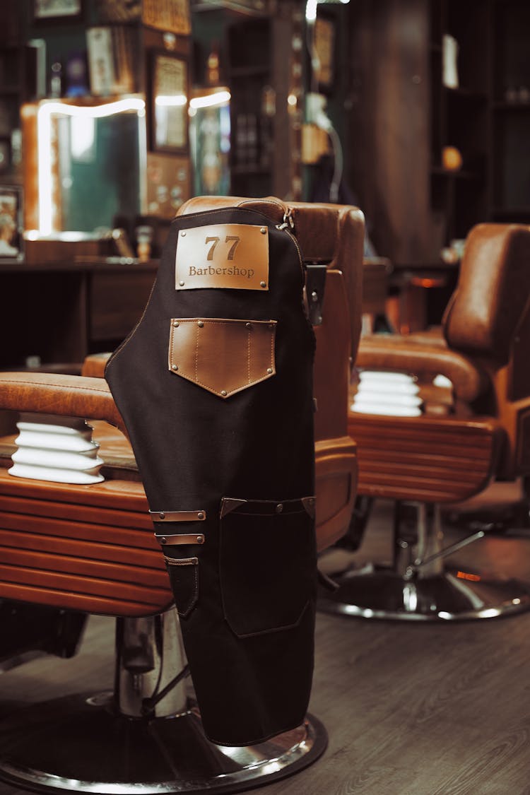 A Brown Apron With Company Name On A Brown Barber Chair