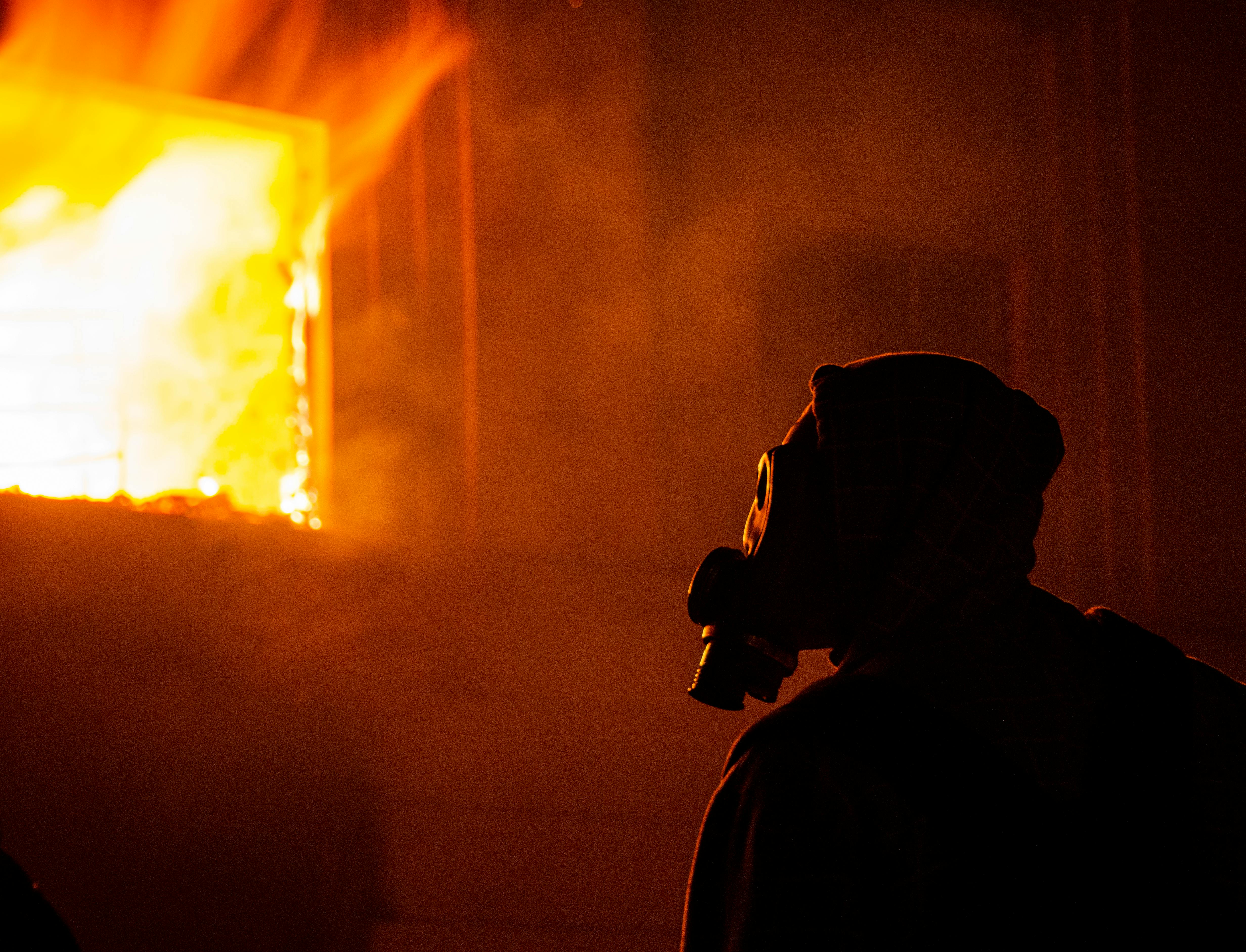 man with face mask looking at a burning establishment