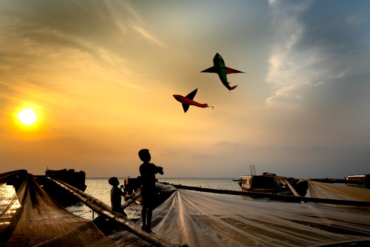 Silhouette Of Kids Playing Kites