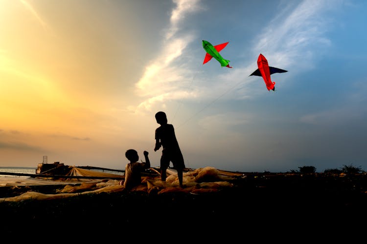 Silhouette Of Kids Playing With Kites