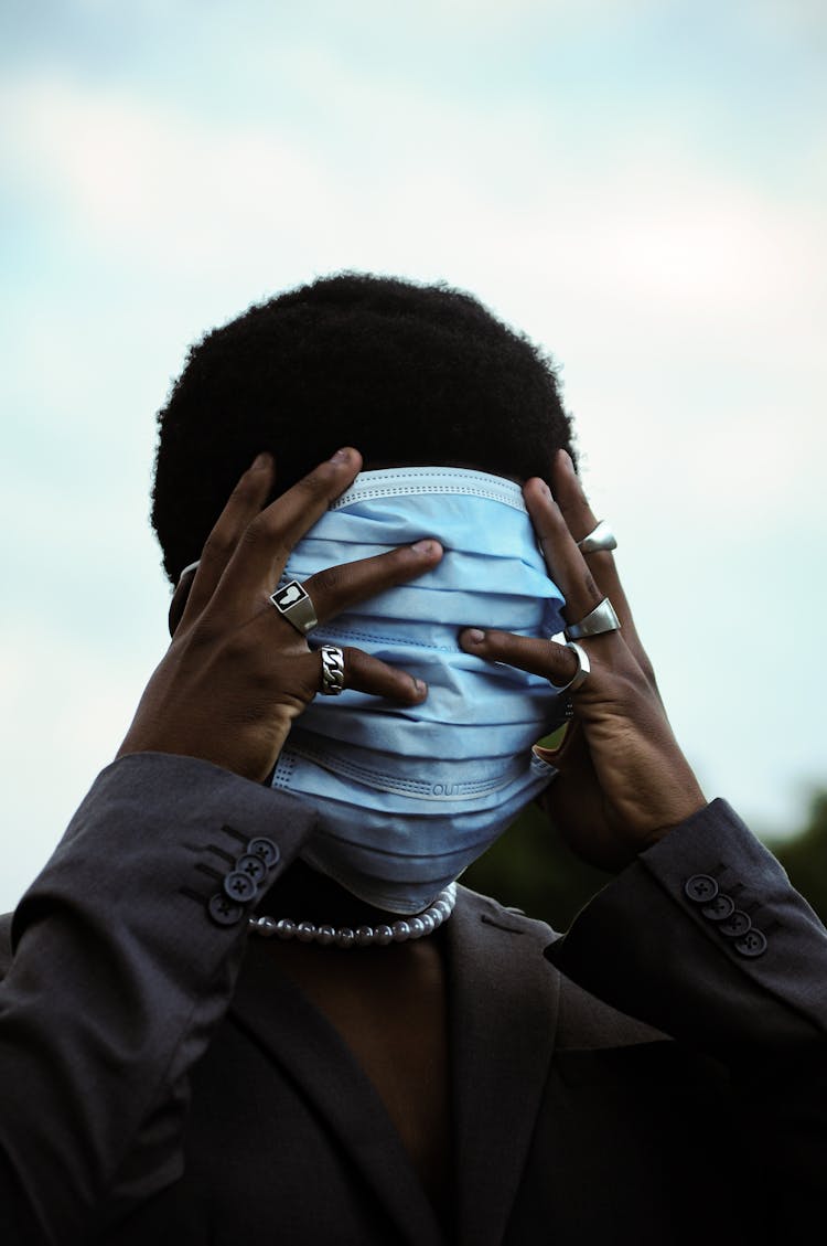 Unrecognizable Young Man Covering Face With Masks