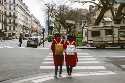 Two Women Wearing Red Coats With Backpacks 