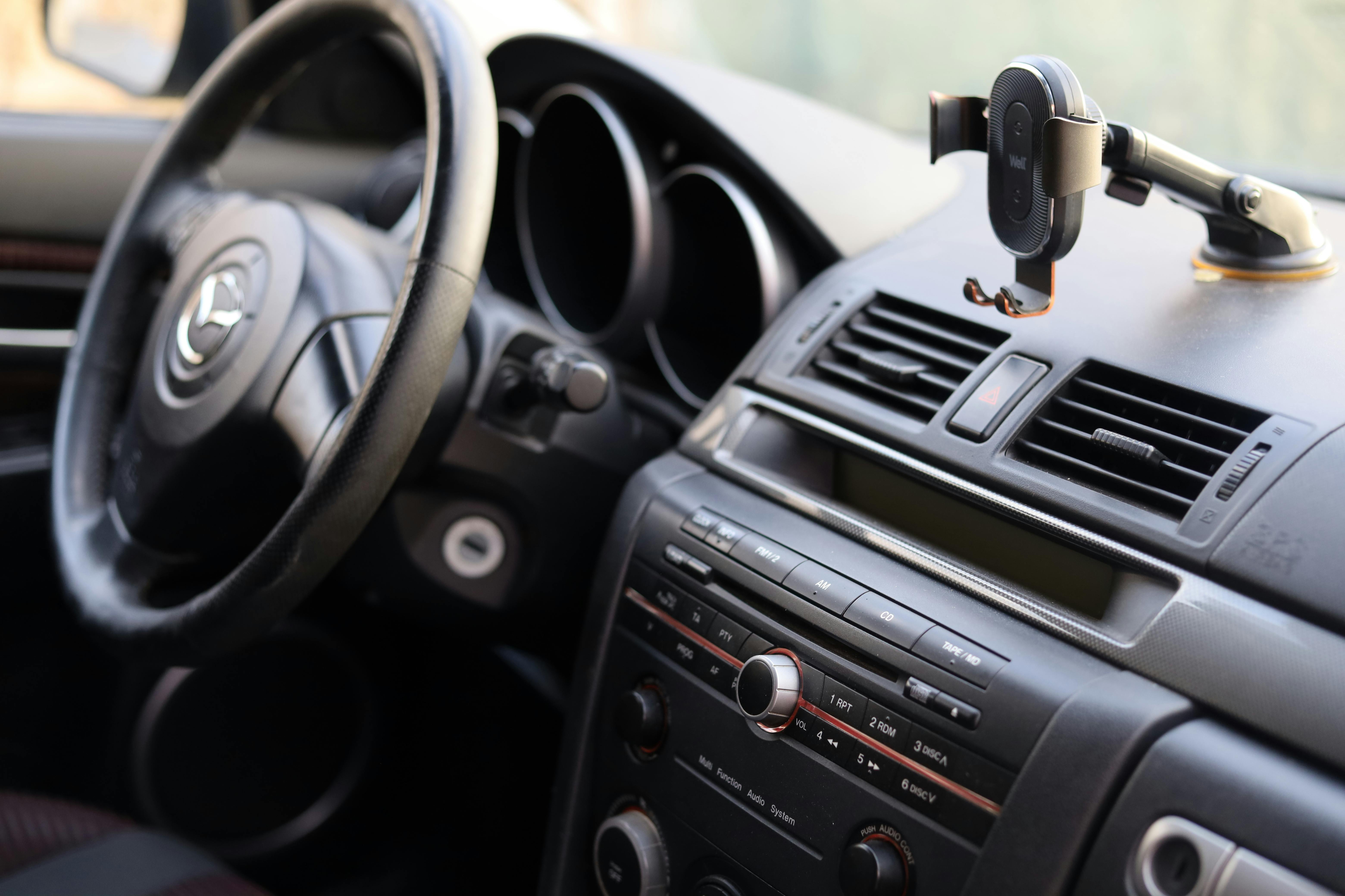 Close-up of a car dashboard featuring a steering wheel and phone holder, ideal for automotive insights.