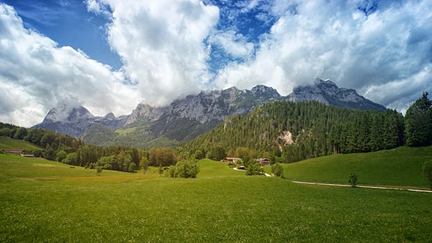 高山风景令人叹为观止，郁郁葱葱的绿色田野、高耸的山脉和蓬松的云朵尽收眼底