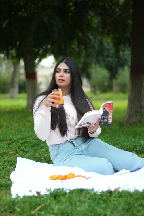 A Woman Holding a Drink and Book