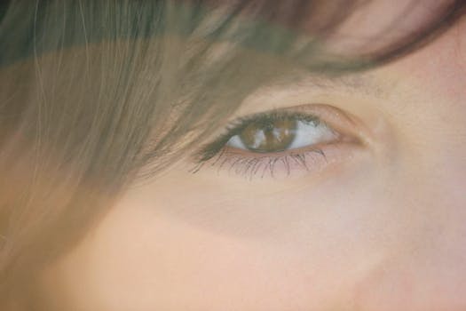 A detailed close-up of a human eye with surrounding facial features in soft, natural lighting.