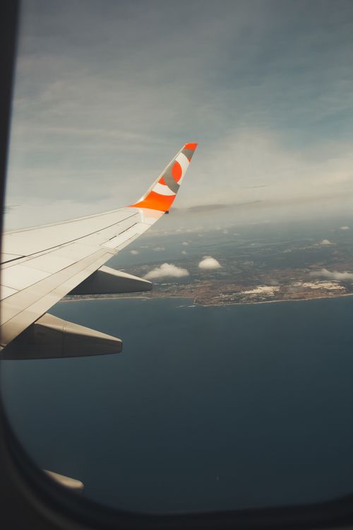 Free A breathtaking view of the coastline captured from an airplane window, showcasing the ocean and sky. Stock Photo