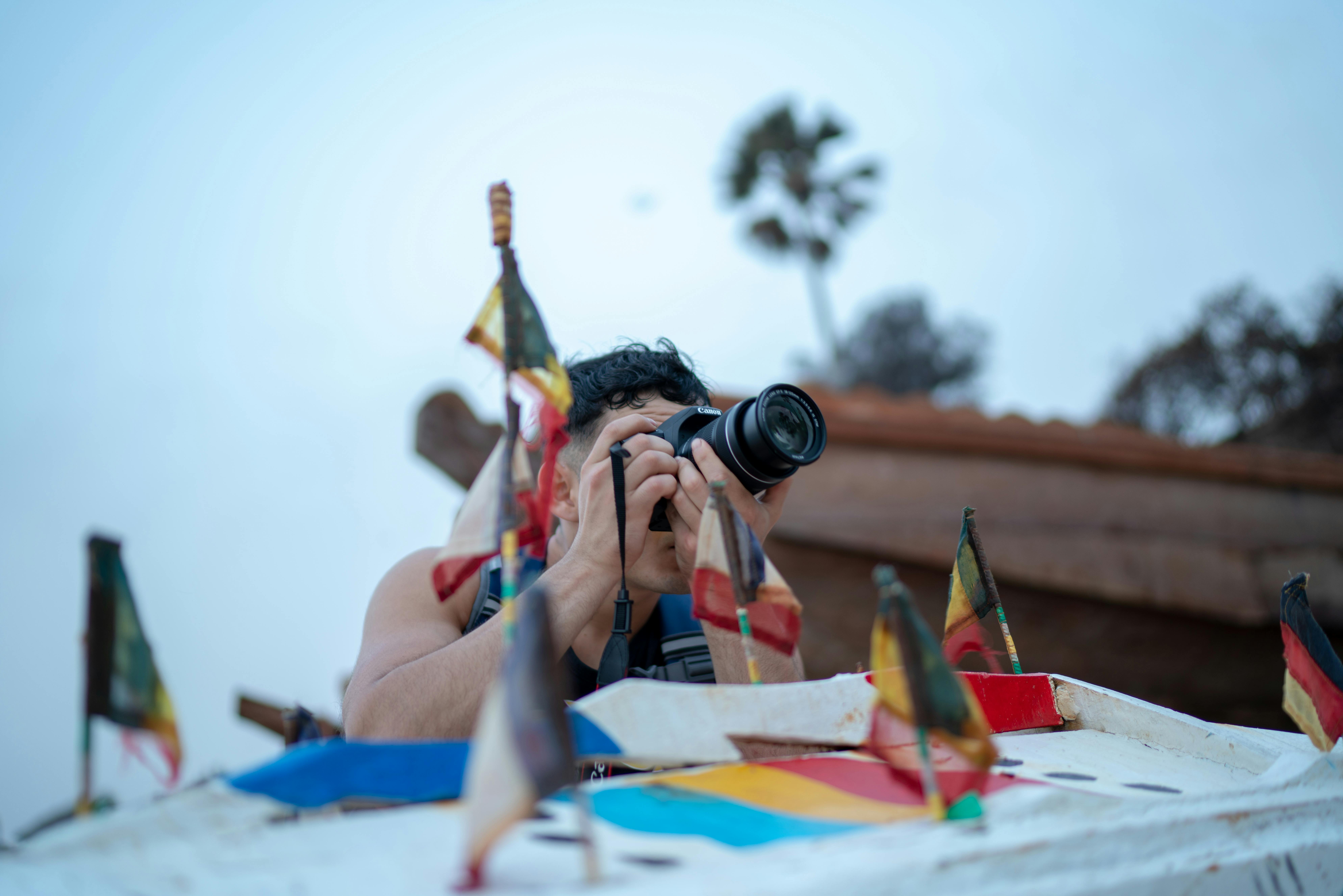 Man Taking Photo Using Dslr Camera Near Country Flag Miniatures
