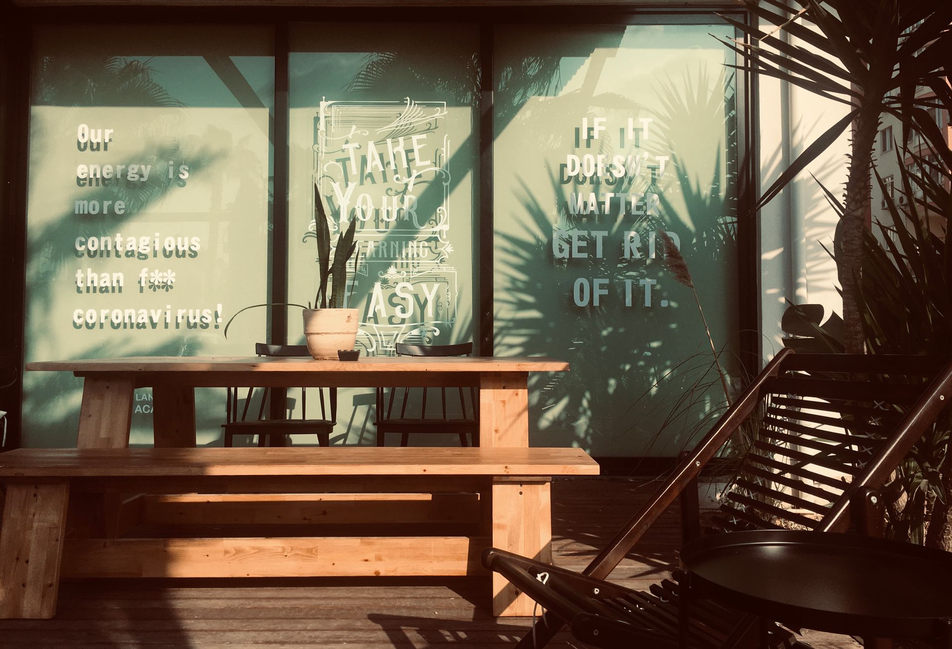 Relaxing outdoor café scene with wooden benches and motivational quotes on glass windows.