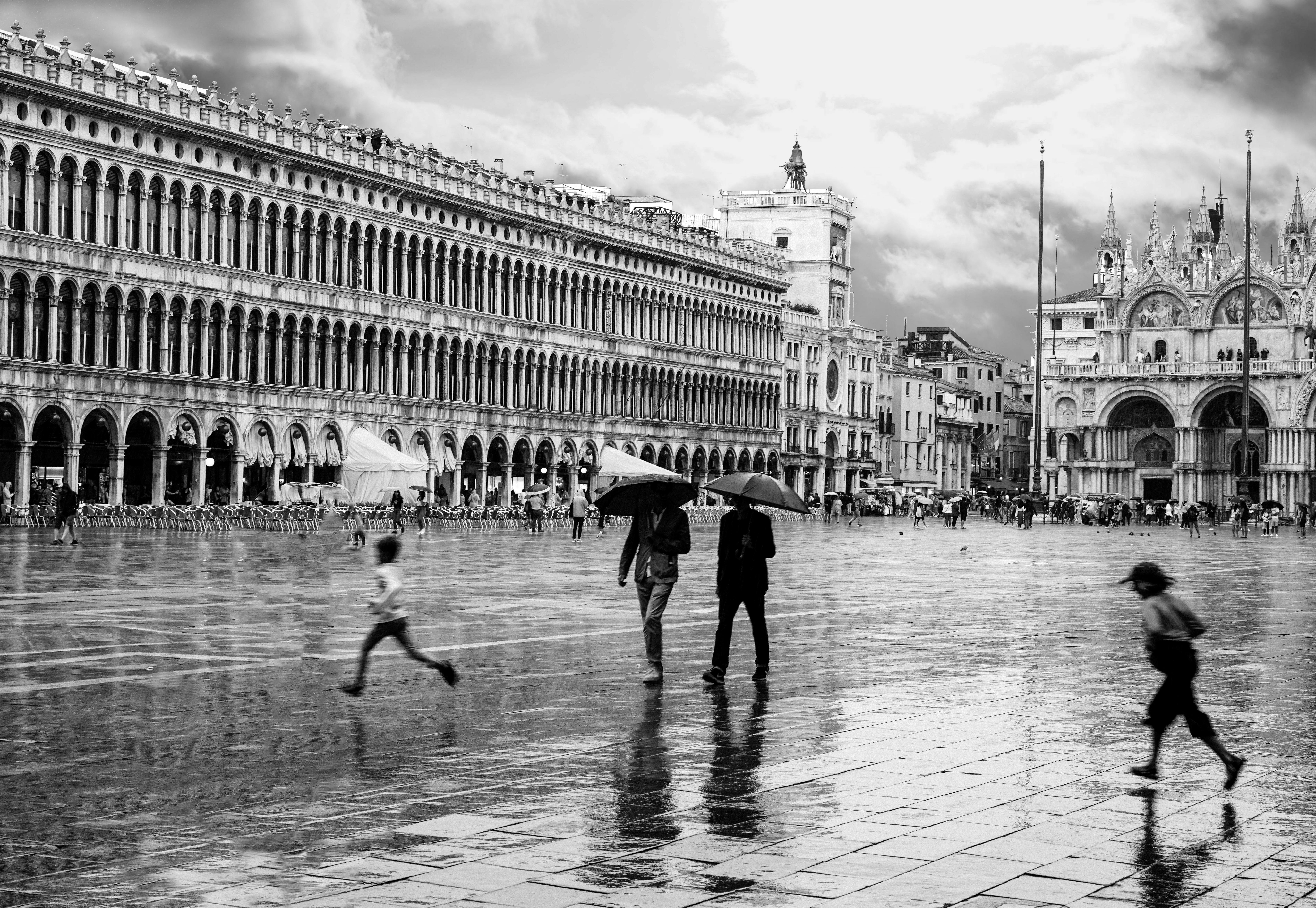 Black and white scene of people with umbrellas at St. Mark